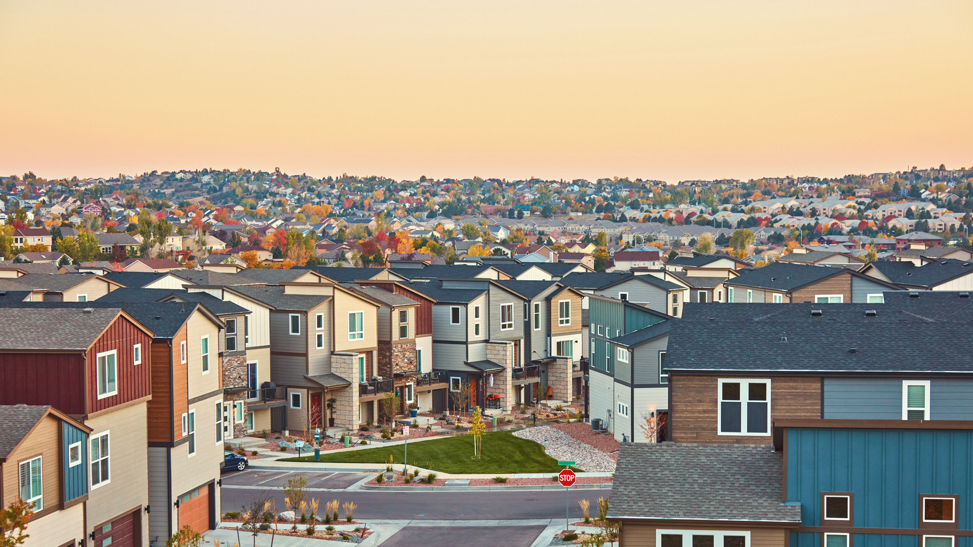 A suburb with rows of colorful houses stretching into the distance during twilight.